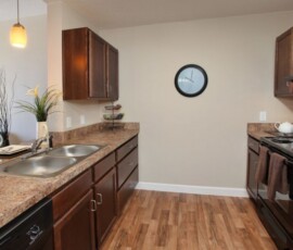 Modern kitchen with dark wood cabinets, double sink and hardwood floors at The Ella