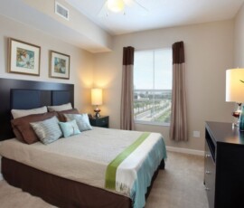 Spacious bedroom with ceiling fan, large window and city views at The Ella