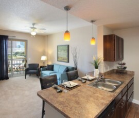 Open concept living room and kitchen with pendant lights and balcony at The Ella