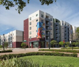 Street-level exterior view of The Trio at ENCORE! with colorful mural facade