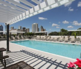 Rooftop pool with lounge chairs and panoramic Tampa skyline view at The Trio