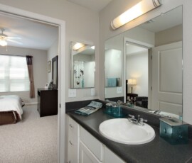 Bathroom with dark granite vanity and large mirror at The Trio at ENCORE!
