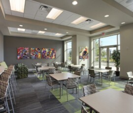 Clubroom with dining tables, chairs, and colorful artwork on the walls