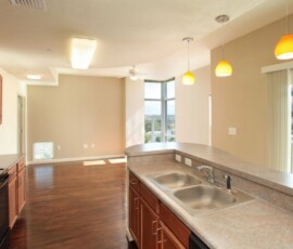 Apartment kitchen with double sink, granite countertops, and yellow pendant lights