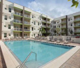 Resort-style pool surrounded by lounge chairs and apartment balconies