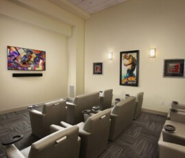 Private theater room with reclining seats and movie poster wall decor
