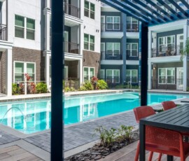 Courtyard pool with lounge seating and pergola at Legacy ENCORE! Luxury Apartments
