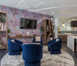 Upscale resident lounge with blue velvet chairs and decorative wallpaper at Legacy ENCORE!
