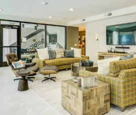 Modern resident clubroom with plaid sofas, Eames chair and wall-mounted TV at Navara at ENCORE!