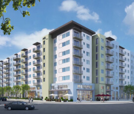 Multi-story residential apartment building exterior with white and sage green facade, dark roof overhangs, retail storefronts at street level, parked cars, blue sky with clouds.